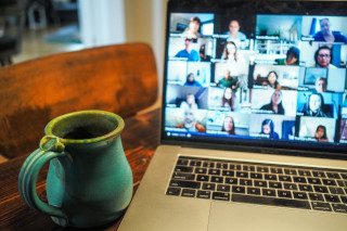Laptop full of people on an online call, with a teal mug beside it